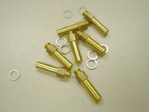 Sechs goldene Messingteile zusammen mit weißen Unterlegscheiben auf einer neutralen Oberfläche, möglicherweise Bestandteil eines Umbausatzes von Remeha.